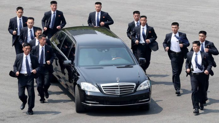 FILE PHOTO: Security personnel run alongside the vehicle carrying North Korean leader Kim Jong Un at the truce village of Panmunjom